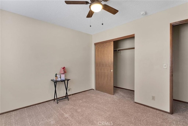 unfurnished bedroom with ceiling fan, a textured ceiling, a closet, and light carpet