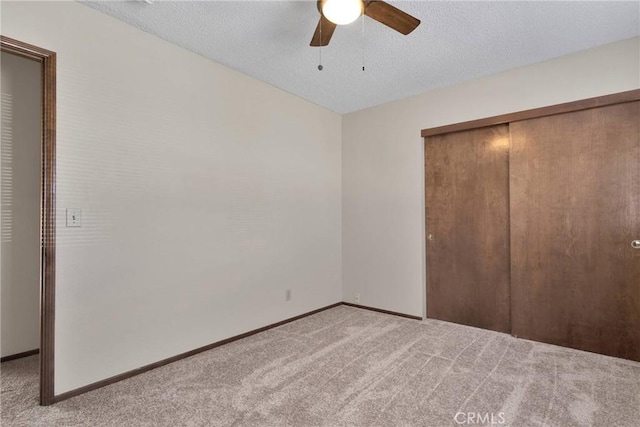 unfurnished bedroom featuring ceiling fan, light colored carpet, a textured ceiling, and a closet