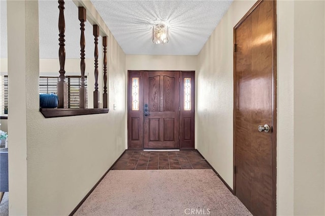 entryway featuring dark carpet and a textured ceiling