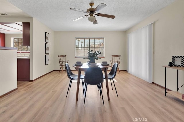 dining room with light hardwood / wood-style floors, a textured ceiling, and ceiling fan