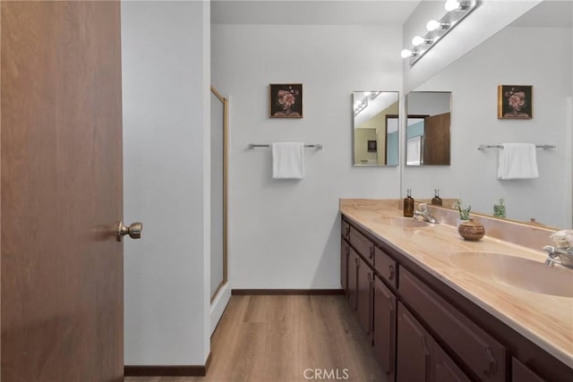 bathroom with a shower with shower door, hardwood / wood-style flooring, and vanity