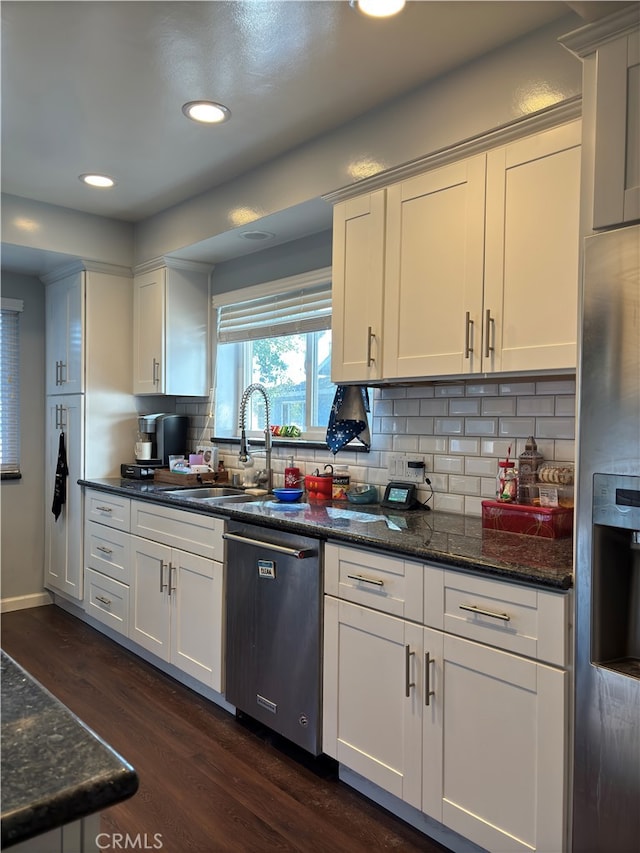 kitchen with white cabinetry, appliances with stainless steel finishes, dark hardwood / wood-style floors, dark stone countertops, and sink