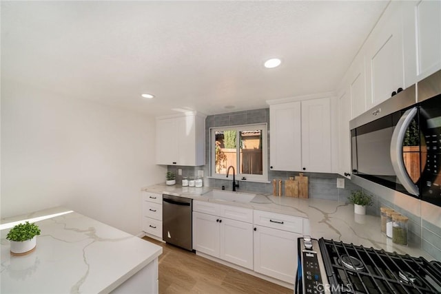 kitchen featuring stainless steel appliances, white cabinets, and light stone counters