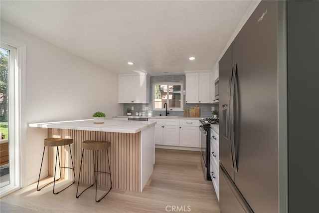 kitchen with white cabinetry, stainless steel appliances, a kitchen island, a breakfast bar, and sink