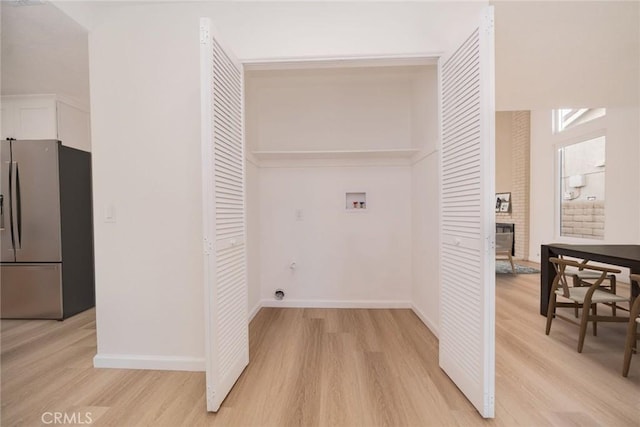 washroom with light wood-type flooring, a fireplace, and hookup for a washing machine