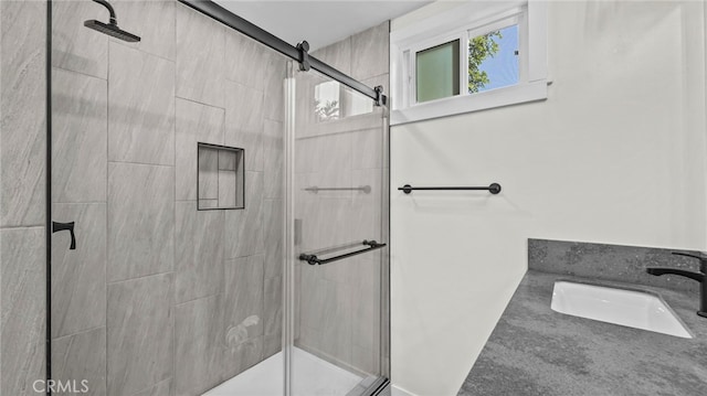 bathroom featuring a shower with shower door and sink