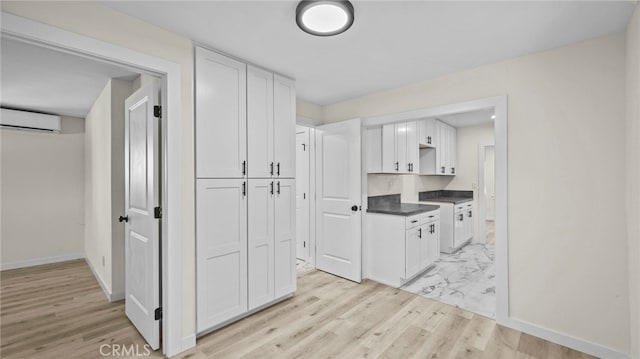 kitchen featuring an AC wall unit and white cabinetry