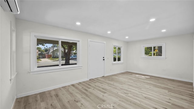 interior space with a wall mounted AC and light hardwood / wood-style floors