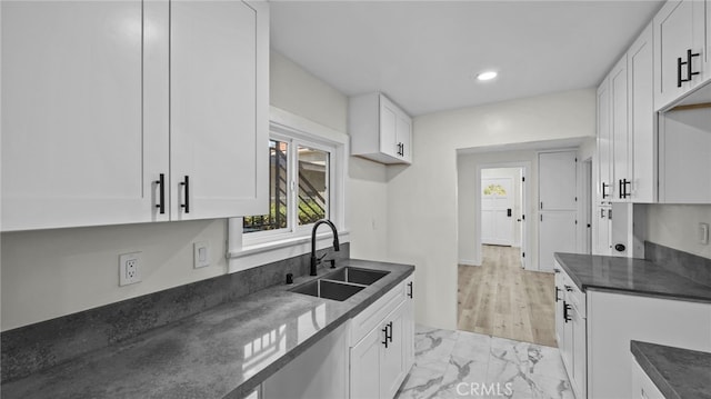 kitchen with white cabinets, dark stone counters, and sink