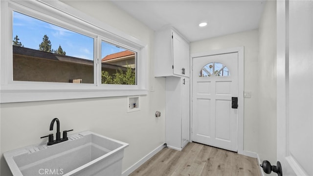 laundry area with cabinets, sink, hookup for a washing machine, and light wood-type flooring