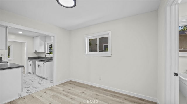 kitchen featuring light wood-type flooring, white cabinetry, and sink