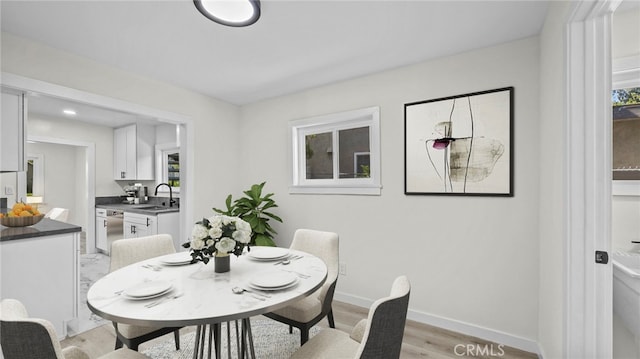 dining space with light wood-type flooring and sink