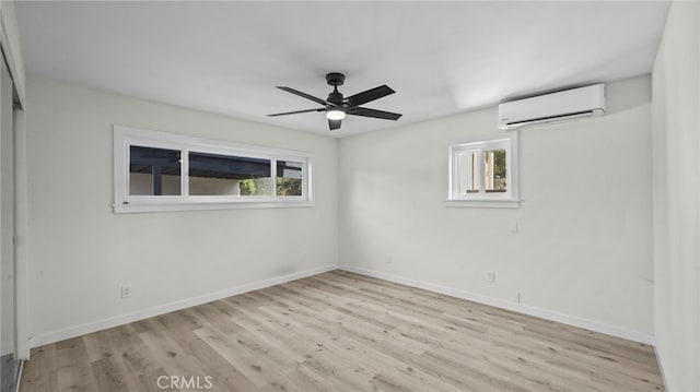 empty room with ceiling fan, a healthy amount of sunlight, light hardwood / wood-style floors, and a wall mounted air conditioner