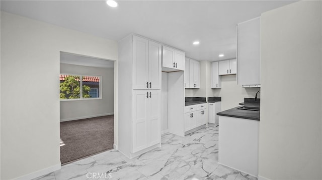 kitchen featuring sink, light colored carpet, and white cabinets