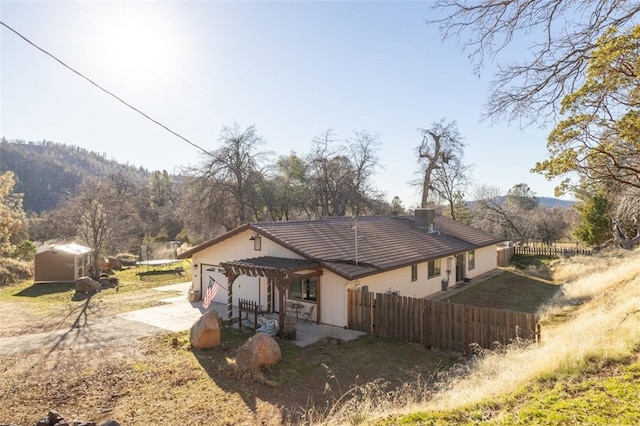 back of property featuring a mountain view, a shed, and a pergola