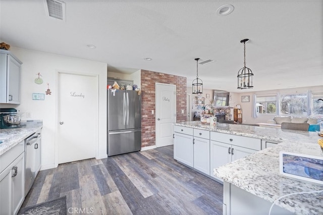 kitchen featuring decorative light fixtures, dark hardwood / wood-style floors, appliances with stainless steel finishes, light stone counters, and a chandelier