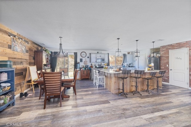 dining room featuring a textured ceiling, dark wood-type flooring, and wood walls