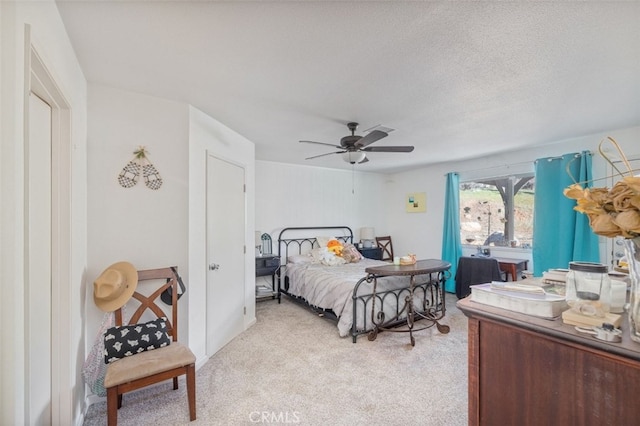 bedroom featuring ceiling fan, light carpet, and a textured ceiling