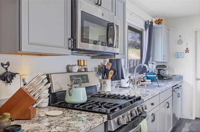 kitchen featuring appliances with stainless steel finishes, sink, and light stone counters