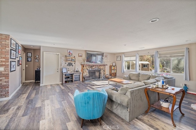 living room with hardwood / wood-style floors and a stone fireplace