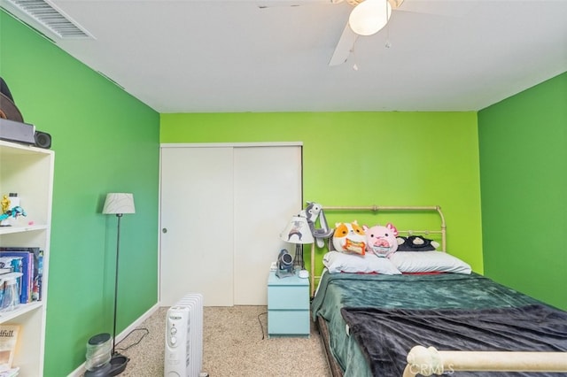 bedroom with ceiling fan, light colored carpet, a closet, and radiator heating unit