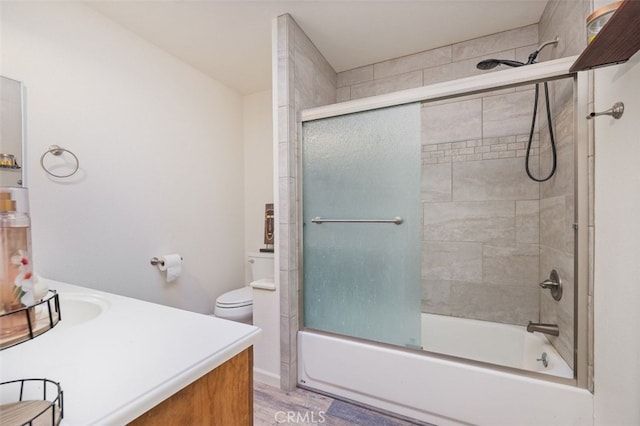 full bathroom with hardwood / wood-style flooring, bath / shower combo with glass door, toilet, and vanity