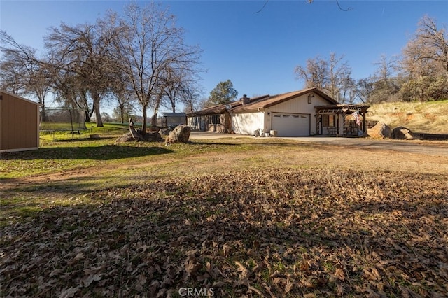 view of home's exterior featuring a lawn, a trampoline, and a garage