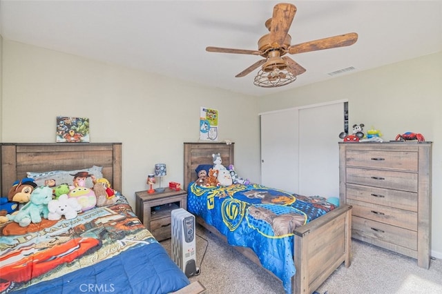 bedroom with ceiling fan, light colored carpet, and a closet