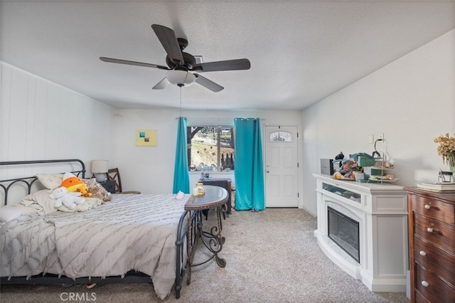 carpeted bedroom featuring ceiling fan and a textured ceiling