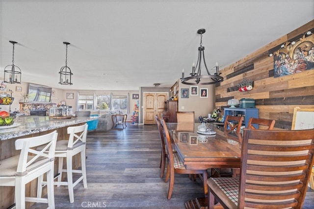 dining space featuring dark wood-type flooring and wood walls