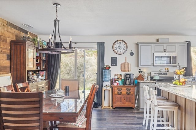 dining room with dark wood-type flooring, wood walls, and a textured ceiling