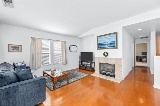 living room with vaulted ceiling, a fireplace, and hardwood / wood-style flooring