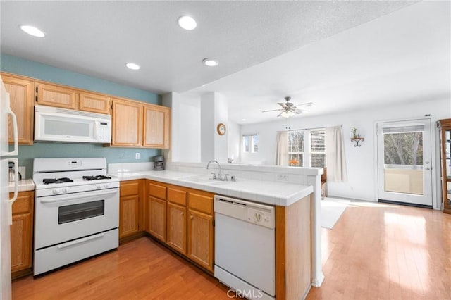 kitchen featuring sink, light hardwood / wood-style floors, kitchen peninsula, and white appliances