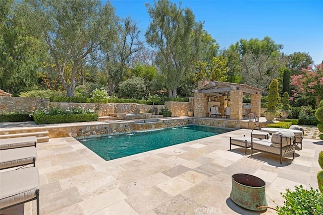 view of swimming pool with an outdoor structure, pool water feature, and a patio