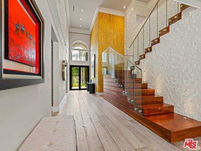 entryway featuring french doors, crown molding, a towering ceiling, and hardwood / wood-style floors