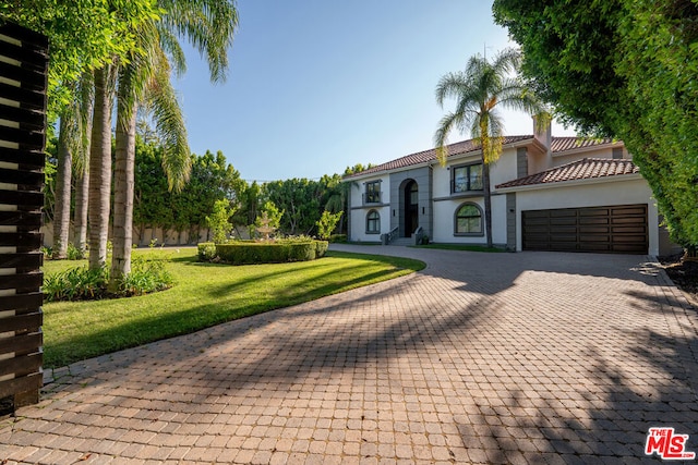 mediterranean / spanish home featuring a front lawn and a garage