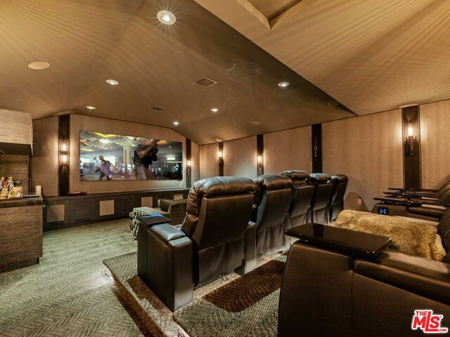 carpeted cinema room with lofted ceiling and wooden walls