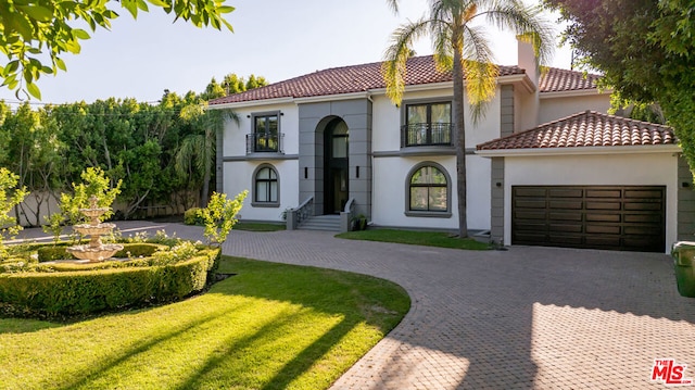 mediterranean / spanish-style house featuring a front yard and a garage