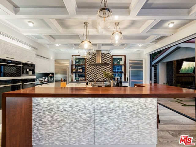 kitchen with built in refrigerator, butcher block countertops, beamed ceiling, and coffered ceiling