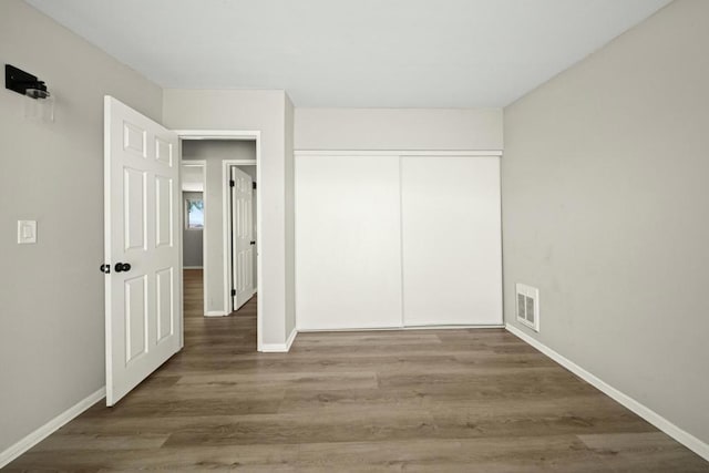 unfurnished bedroom featuring a closet and dark wood-type flooring