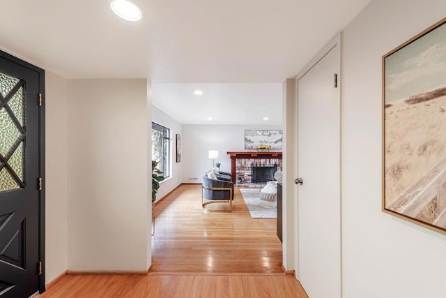 entryway with a brick fireplace and light wood-type flooring