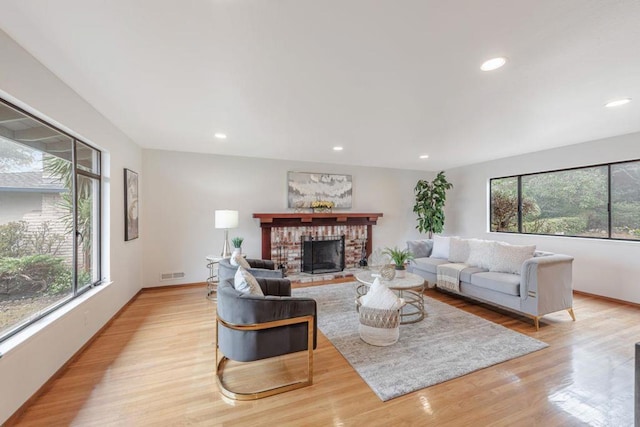 living room featuring a brick fireplace and light wood-type flooring