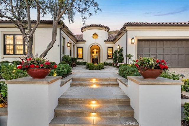 exterior entry at dusk featuring a garage