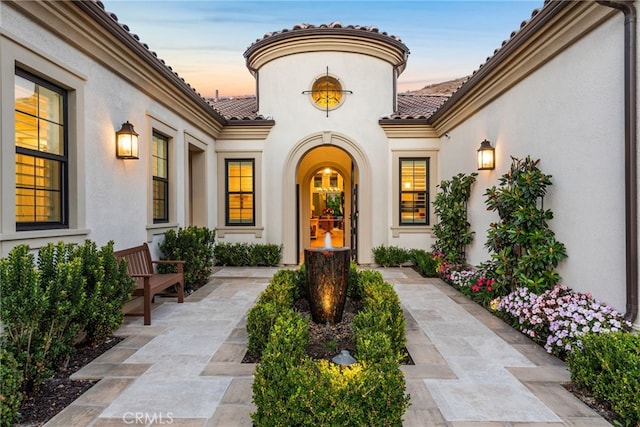 exterior entry at dusk featuring a patio