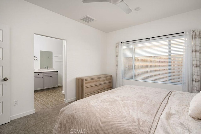 carpeted bedroom featuring ceiling fan, ensuite bath, and sink