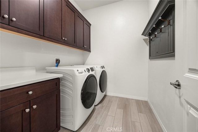 washroom with light hardwood / wood-style flooring, washer and dryer, and cabinets