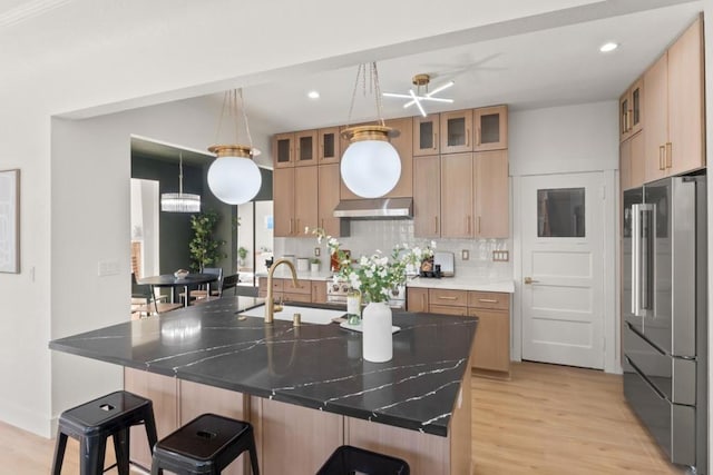 kitchen with decorative light fixtures, backsplash, a breakfast bar, sink, and stainless steel appliances