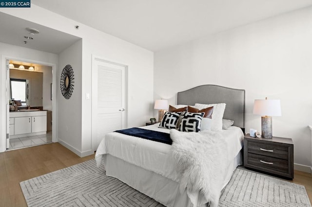 bedroom featuring light wood-type flooring, a closet, and ensuite bath