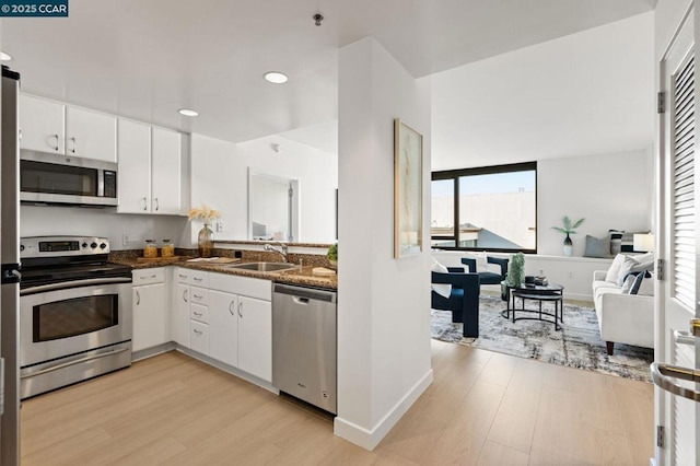 kitchen with sink, dark stone countertops, stainless steel appliances, and white cabinetry