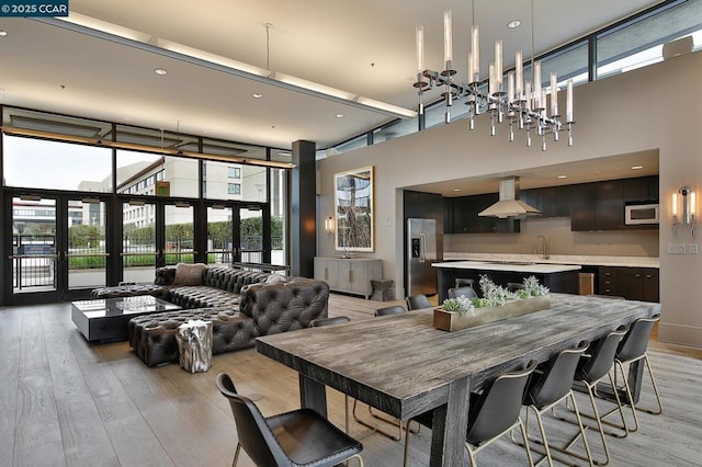 dining area featuring a high ceiling, light hardwood / wood-style flooring, french doors, and a healthy amount of sunlight